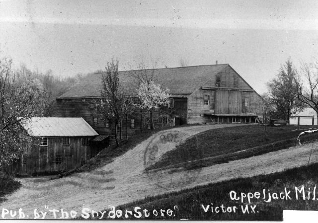 black and white photo of old large wooden structure on a hill off dirt road