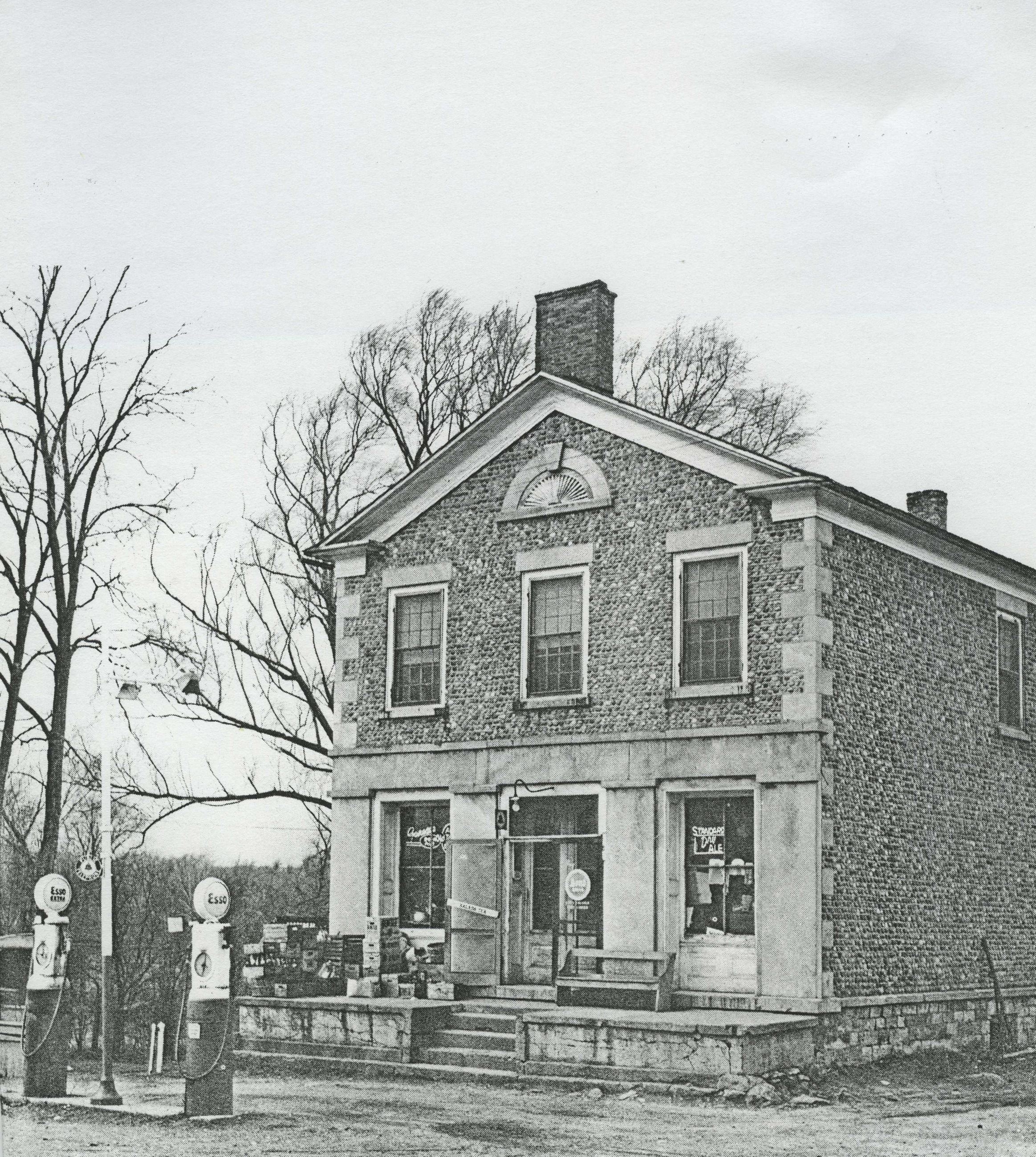 Goldfarbs cobblestone two story building with gas pumps in front